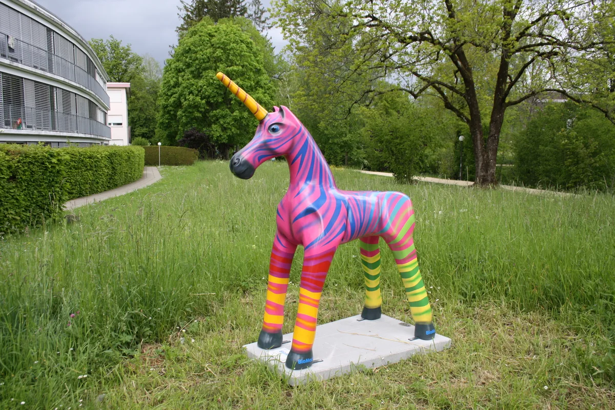 Eine bunte Einhorn-Plastik auf einer Wiese.